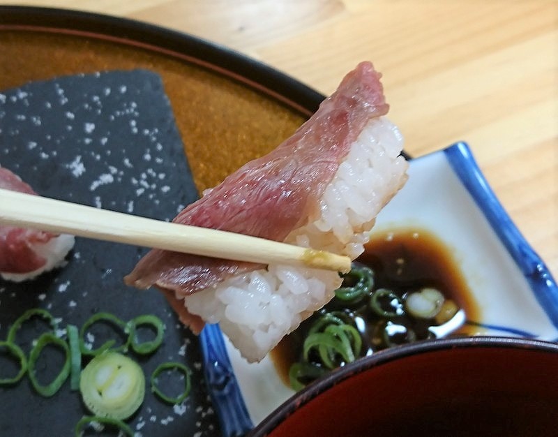 宮崎市の「居酒屋かのこ瓜生野店」の宮崎牛炙り寿司を箸で掴んでいる様子3